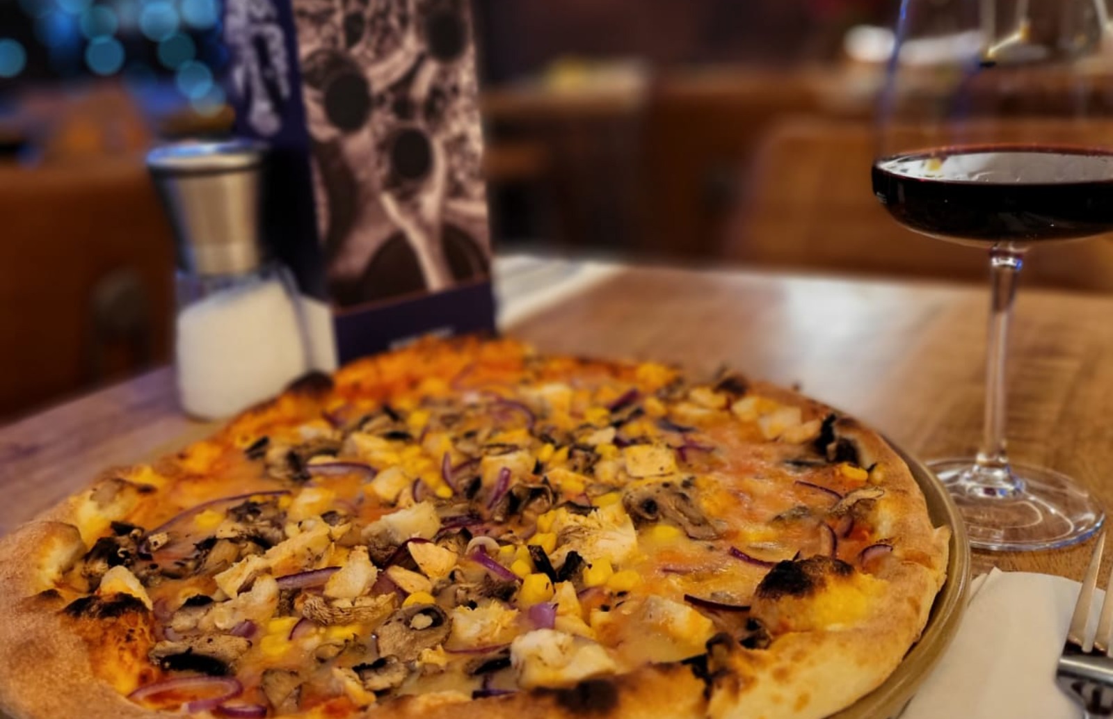 Fresh pizza brought to table with wine